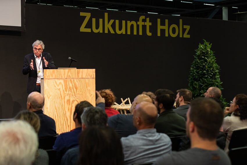 Un porte-parole sur la scène. En arrière-plan, l'inscription "Zukunft Holz" (l'avenir du bois).